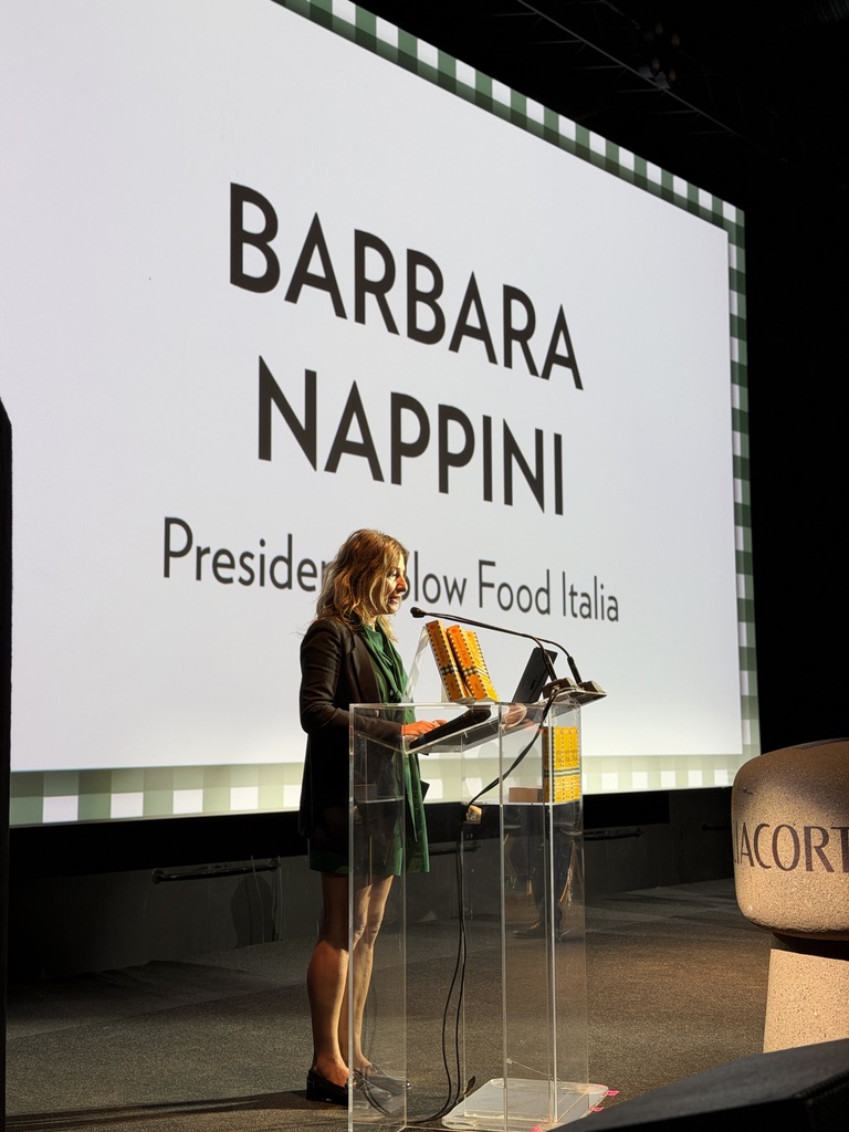 Barbara Nappini, Presidente di Slow Food Italia, parla durante un evento su un palco con uno schermo sullo sfondo.